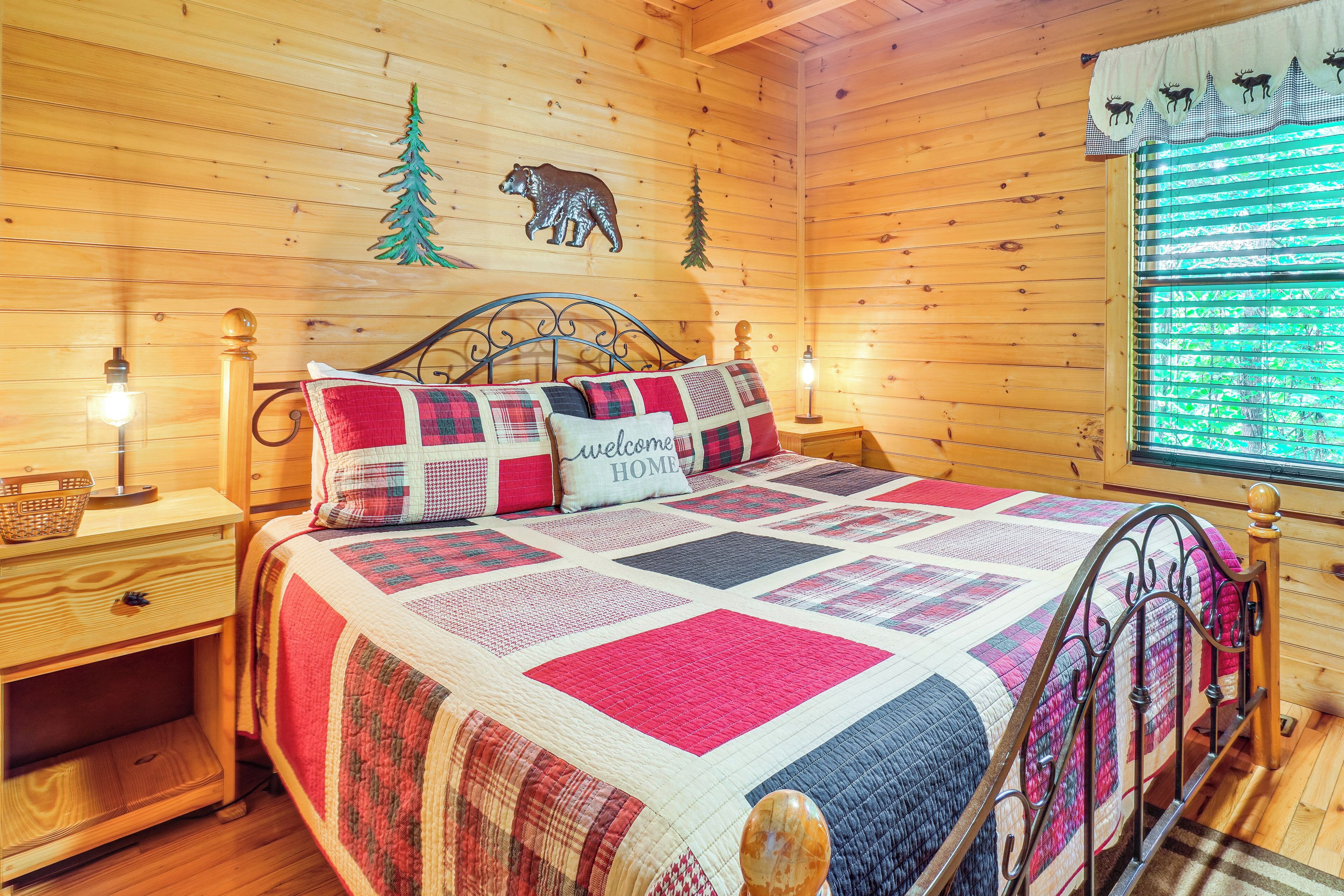 A wooden cabin bedroom with a bed, nightstands, and a window with blinds.