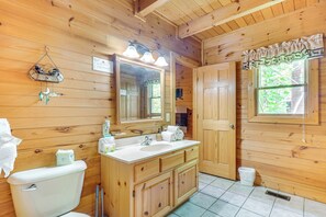 Un bagno in una casetta di legno con lavandino, specchio e toilette.