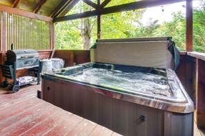 Una vasca idromassaggio con un pontile in legno e un barbecue.