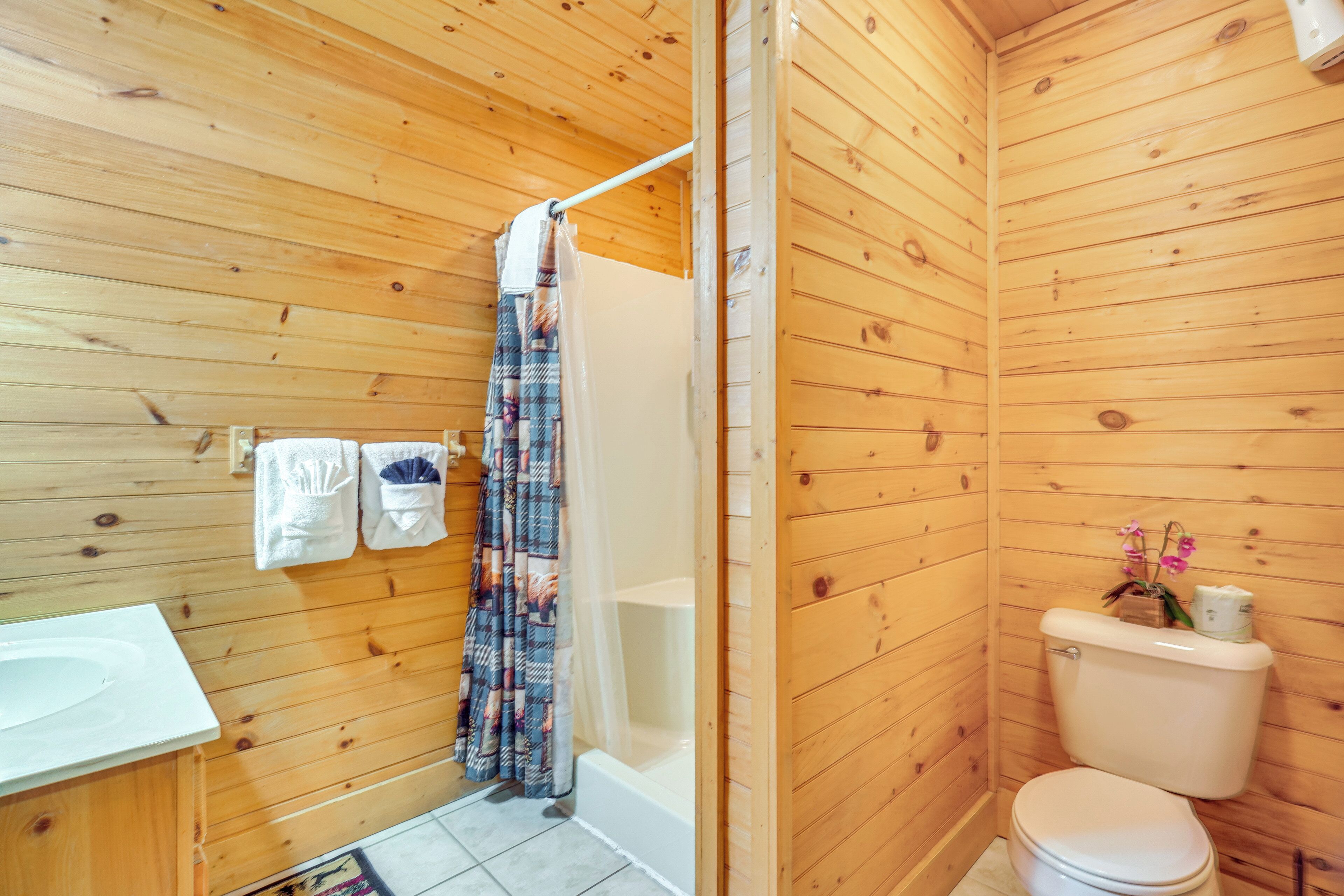 A wooden-paneled bathroom with a bathtub, toilet, and a sink.