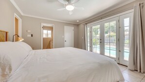 A spacious bedroom with a large bed, a ceiling fan, and a view of a swimming pool through the sliding glass doors. - Shop, Hike & Explore: Fresno Home w/ Private Pool! (Fresno)