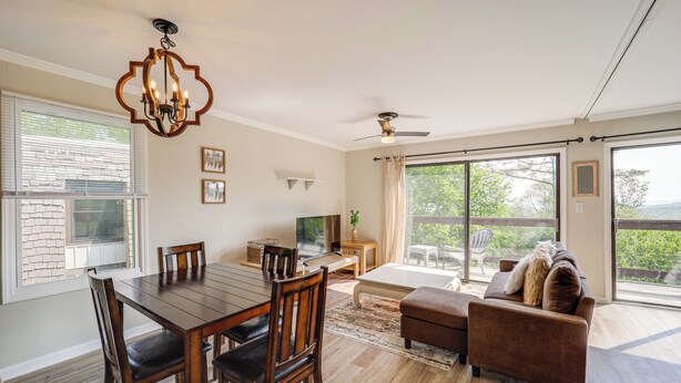 Uma sala de estar espaçosa com área de jantar, janelas amplas e uma varanda.