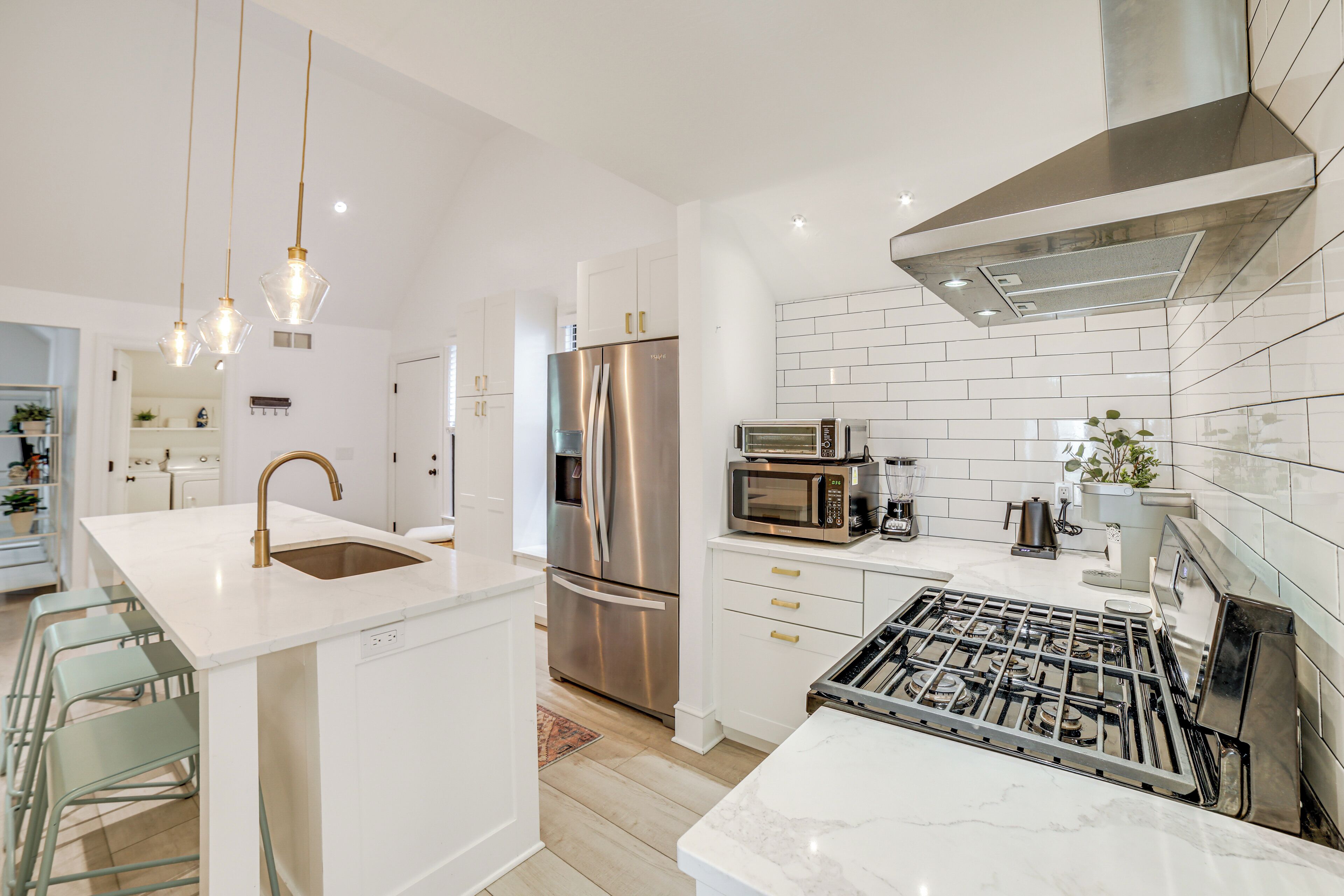 A modern kitchen with white cabinetry, stainless steel appliances, and a central island with a sink.