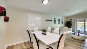A modern living room with a white dining table, white sofas, and a large window. - Colorado River Retreat: Bullhead City Home w/ Deck (Bullhead City)