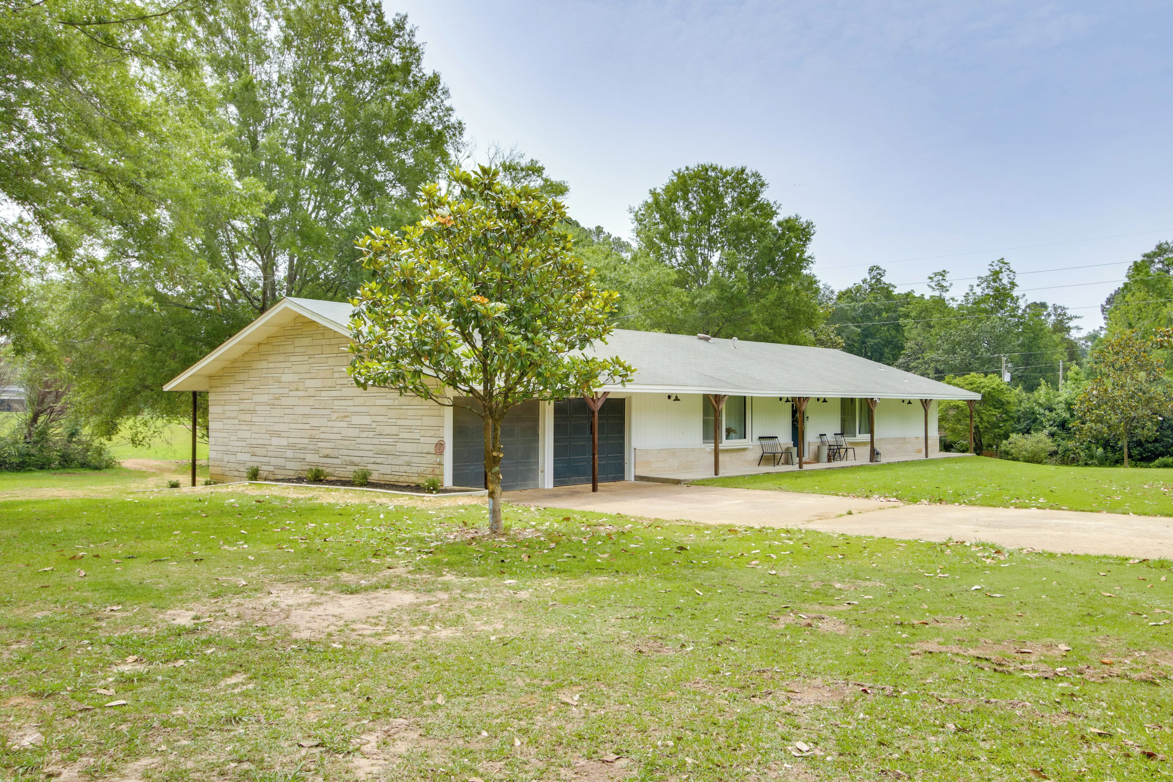 A single-story house with a front porch, a small lawn, and trees in the background.