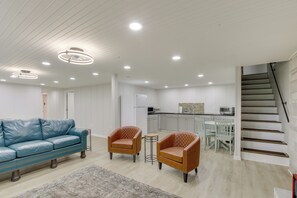 A modern living room with a blue leather sofa, two brown leather armchairs, a small round table, and a staircase leading to the upper floor. - 7 Mi to Tennessee River: Home w/ Patio in Florence (Florence)