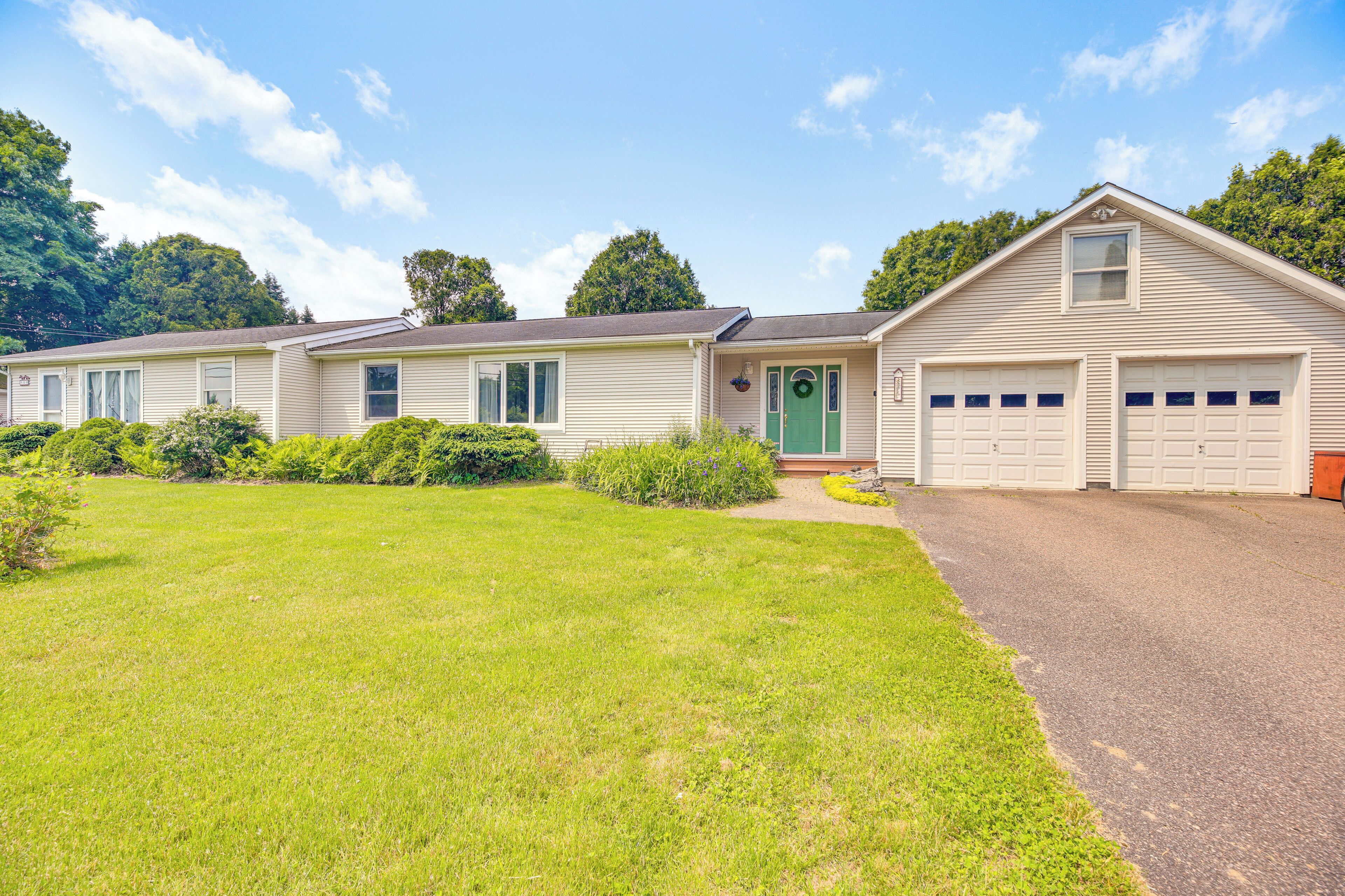 A single-story mobile home with a front garage, a green door, and a well-maintained lawn.