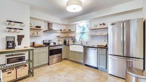 Una cocina moderna con electrodomésticos de acero inoxidable, armarios de madera y un colgador para ollas.
