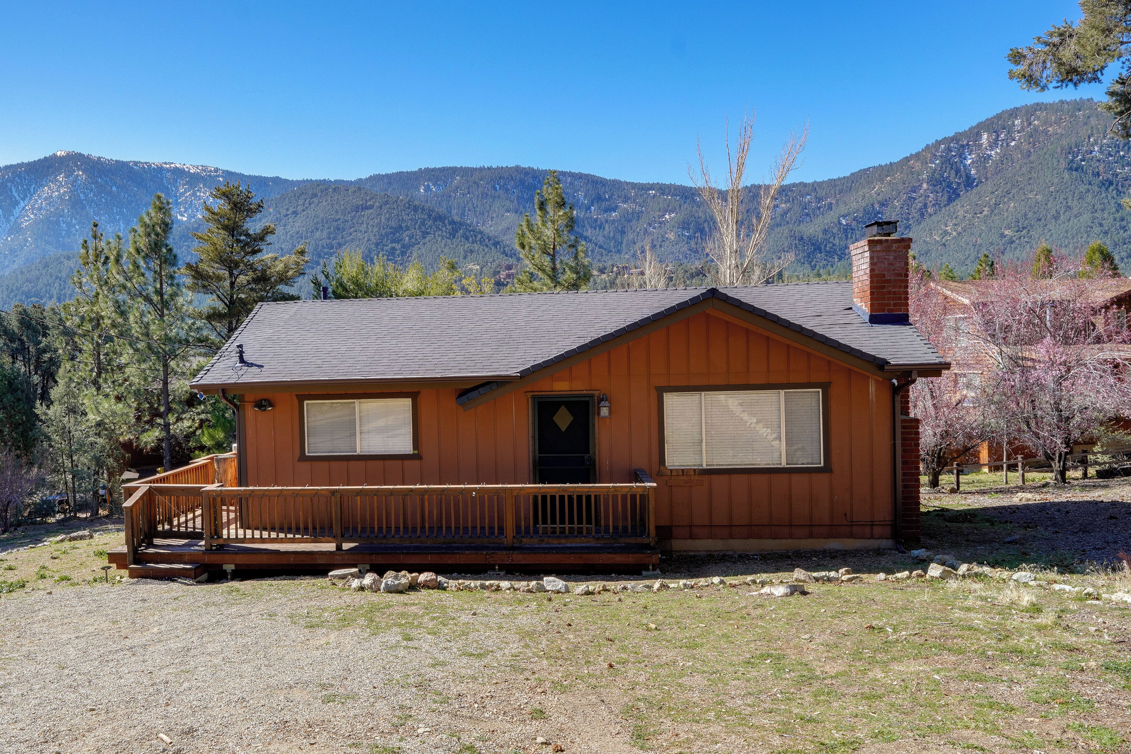 A wooden cabin with a porch, a chimney, and a view of mountains.