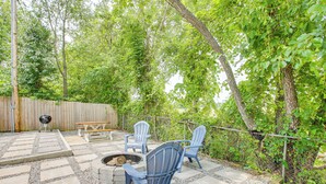 Une terrasse avec un foyer, deux fauteuils Adirondack et une table en bois.