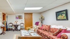 Una sala de estar con una mesa de centro de madera, un sofá floral y un cuadro en la pared.
