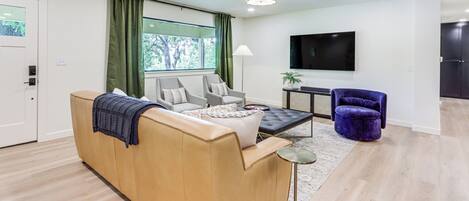 Una sala moderna con un sofá, sillones, una mesa de centro y un televisor.
