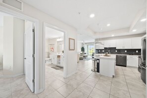 A modern kitchen with white cabinetry, a central island, and a black refrigerator.
