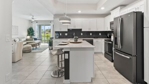 A modern kitchen with white cabinetry, a black refrigerator, and a central island. - Near Disney Magic!Free Parking!Free WI-FI! (Kissimmee)