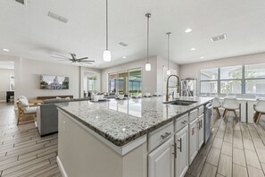 A modern kitchen with a granite countertop, white cabinetry, and a built-in sink.