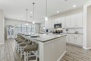 A modern kitchen with white cabinets, a granite countertop, and bar stools.