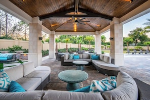 An outdoor patio with a covered seating area, stone flooring, and a ceiling fan. - Stylish Getaway•Pool•Game Room•Near Disney (Kissimmee)