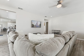 A modern living room with a sofa, a fluffy white throw, and a framed picture on the wall. - Stylish Getaway•Pool•Game Room•Near Disney (Kissimmee)
