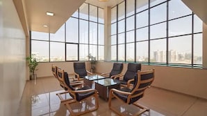 A spacious meeting room with large windows, a glass table, and comfortable chairs. - Hotel Classique, Rajkot (Rajkot)