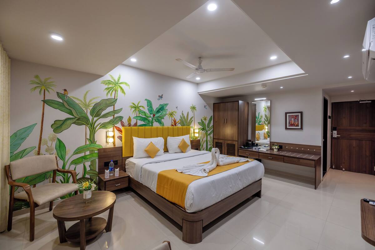 A modern hotel room with a large bed, a desk, and a seating area.