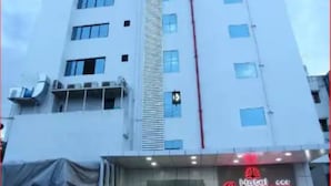 A tall, white building with multiple windows and a red vertical line on the facade. - Hotel Classique, Rajkot (Rajkot)