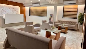 A modern hotel lobby with a reception desk, seating area, and large windows with blinds. - Hotel Classique, Rajkot (Rajkot)