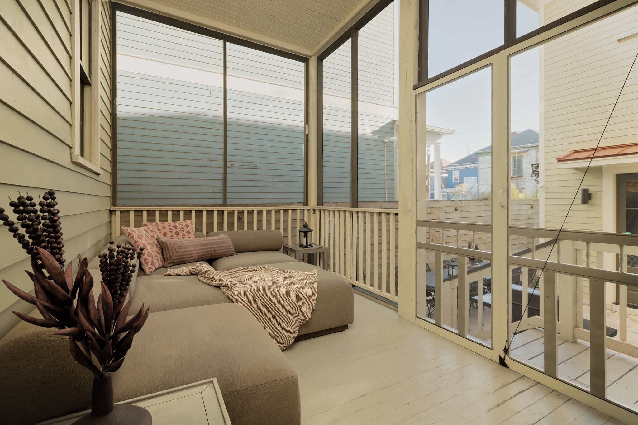 A balcony with a cushioned seating area, a small table with a lantern, and a potted plant.