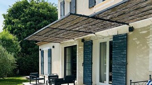 Uma casa moderna com um pátio, área de estar externa e uma grande árvore ao fundo.