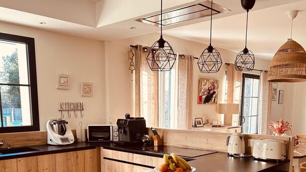 Uma cozinha moderna com armários de madeira, uma ilha central e um espaço de refeições com mesa e cadeiras.