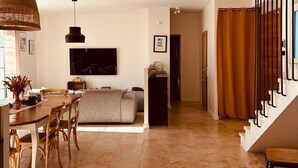Uma sala moderna com área de refeições, escada e TV fixada na parede.