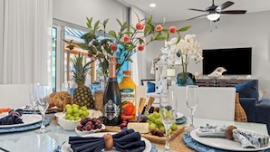 A dining table set with plates, glasses, and a fruit arrangement.