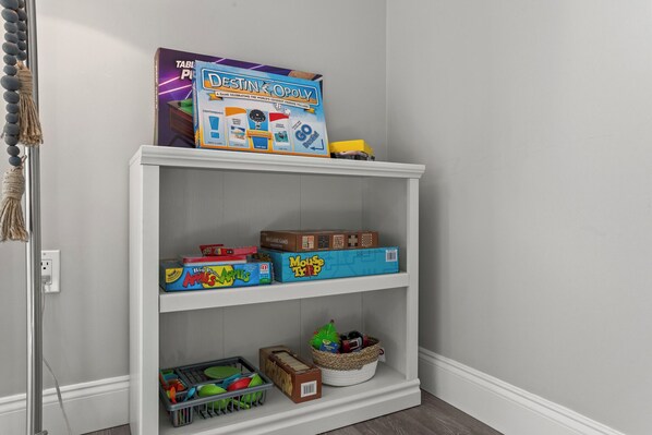 A white bookshelf with various board games and toys.