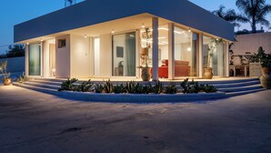 Una casa moderna amb teulada plana, grans finestres de vidre i interior ben il·luminat.