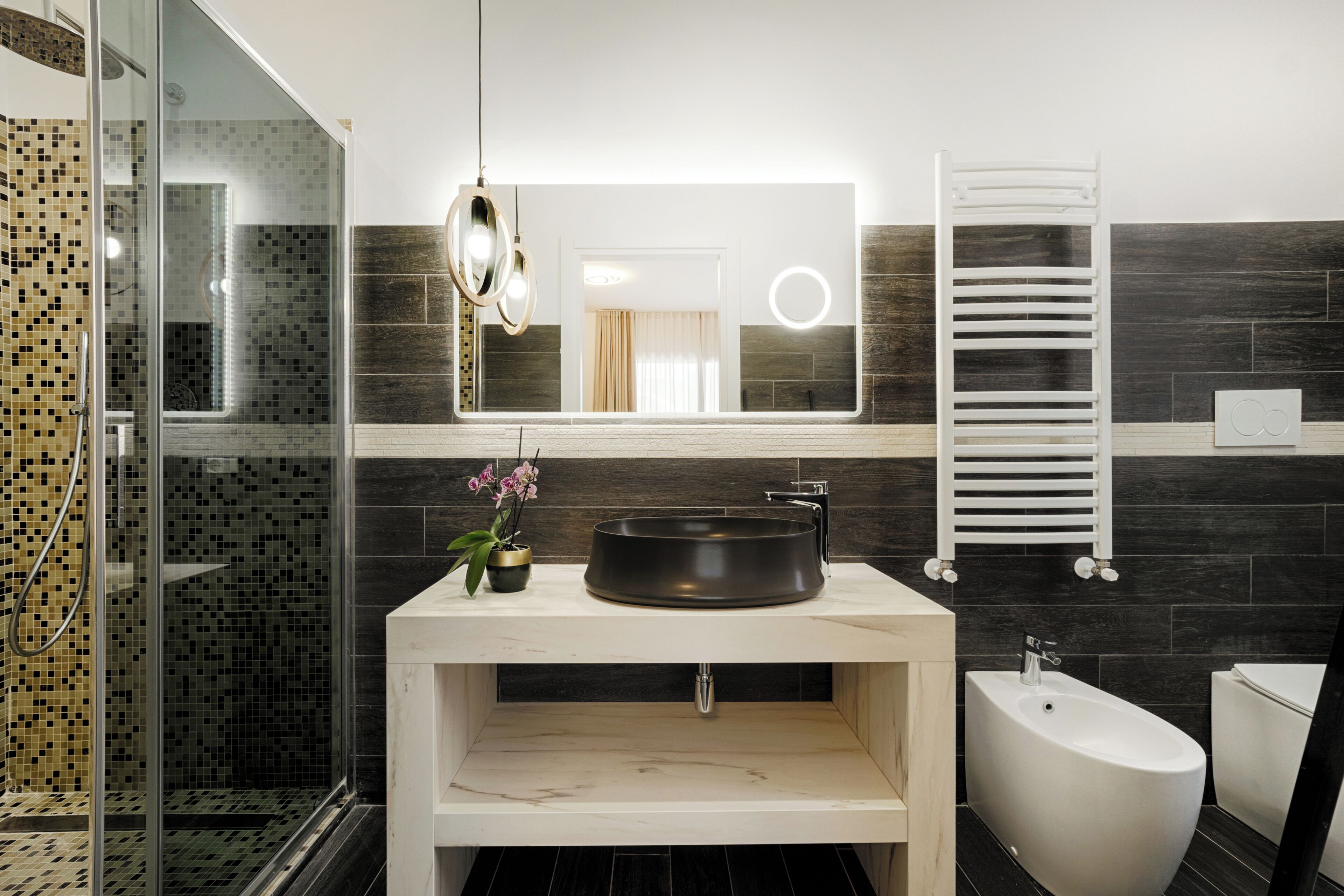 A modern bathroom with a glass shower enclosure, a freestanding bathtub, and a vanity with a black basin.