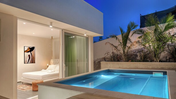 Zona de piscina exterior moderna amb dormitori envidriat i vista al paisatge circumdant.