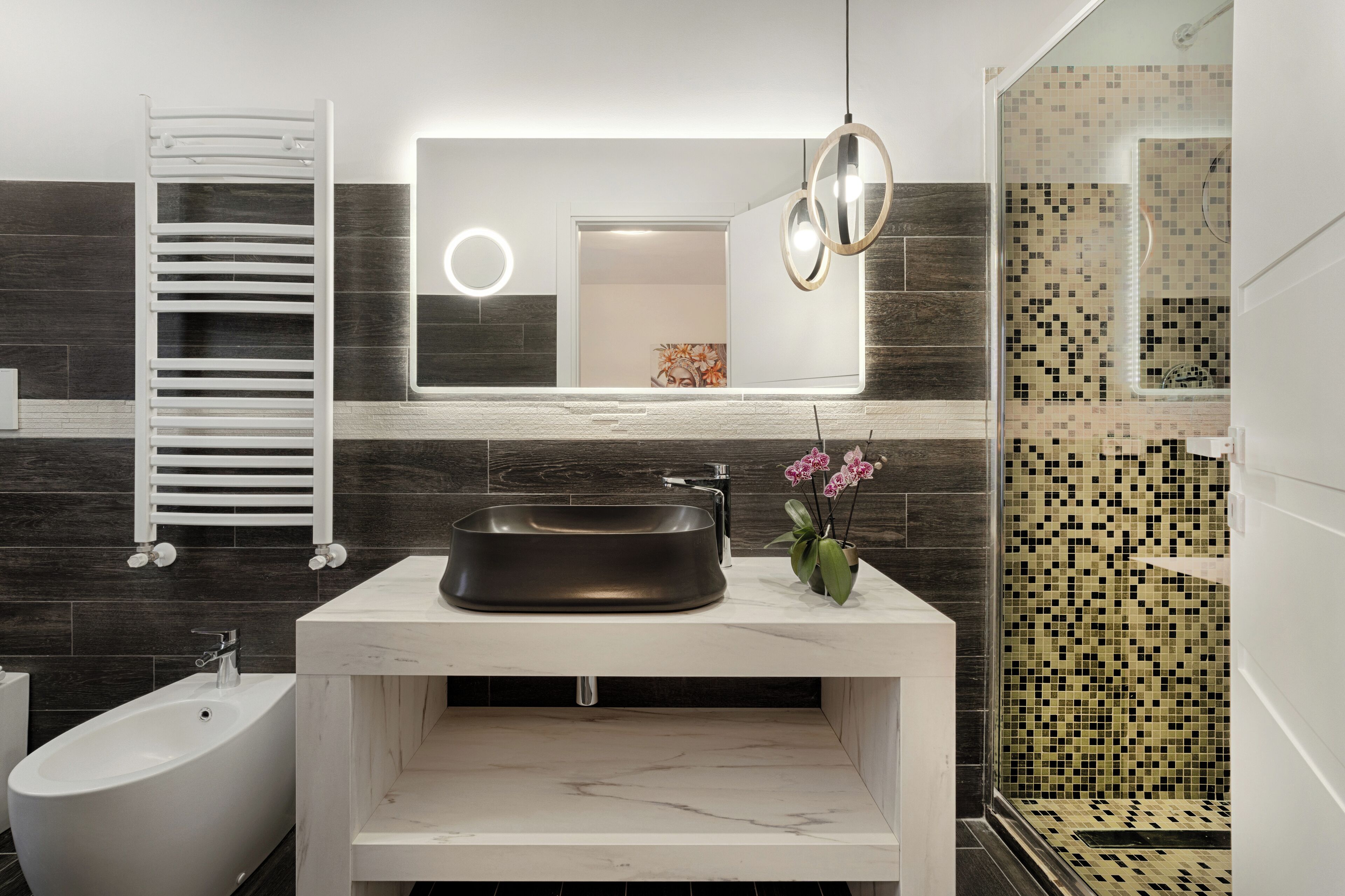 A modern bathroom with a dark wood vanity, a white sink, and a freestanding bathtub.