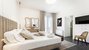 Una habitació d'hotel moderna amb un llit gran, un tocador amb mirall, televisió de pantalla plana i vistes a la ciutat.