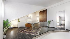 Un interior modern amb barana de vidre, paviment fosc i una zona d'estar central amb taula rodona i cadires.