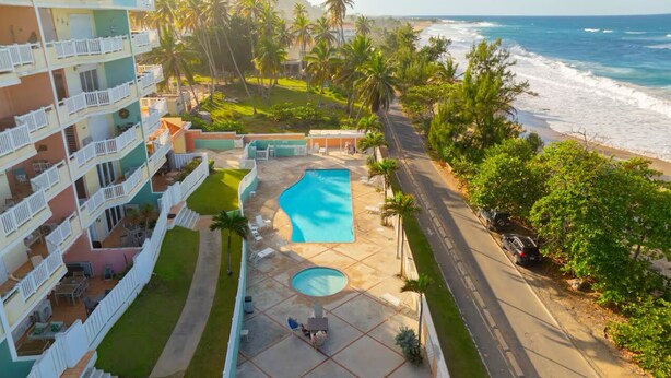Un hotel con piscina, vista al mar y un edificio de varios pisos con balcones.