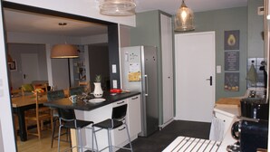 A compact kitchen with a refrigerator, a coffee machine, and bar stools.