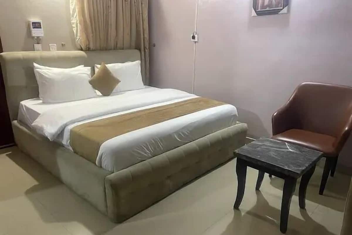 Un letto con testiera, un comodino e una sedia.