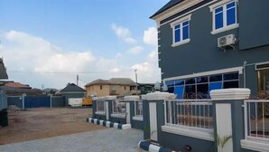 A residential area with a paved driveway leading to a house with a gated entrance. - Double Crown Hotels (Abeokuta)