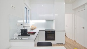 A modern kitchen with white cabinets, a built-in oven, and a small island with a sink. - Aether Athens Luxurious Fully Renovated Apt (Athina)