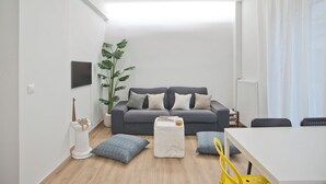 A modern living room with a grey sofa, a white coffee table, and a large plant. - Aether Athens Luxurious Fully Renovated Apt (Athina)