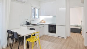 A modern kitchen with white cabinets, a built-in oven, and a dining area with a white table and two chairs. - Aether Athens Luxurious Fully Renovated Apt (Athina)