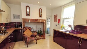 Une cuisine avec une chaise en bois, une cheminée et une fenêtre.