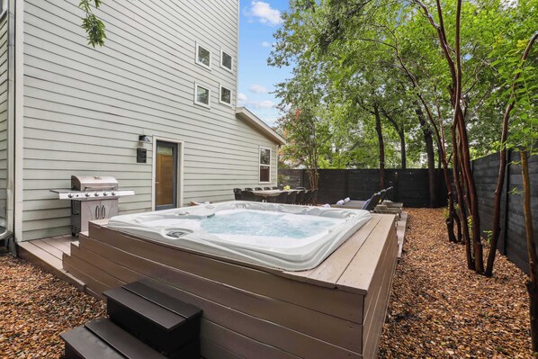 A backyard with a hot tub, outdoor seating, and a barbecue grill.