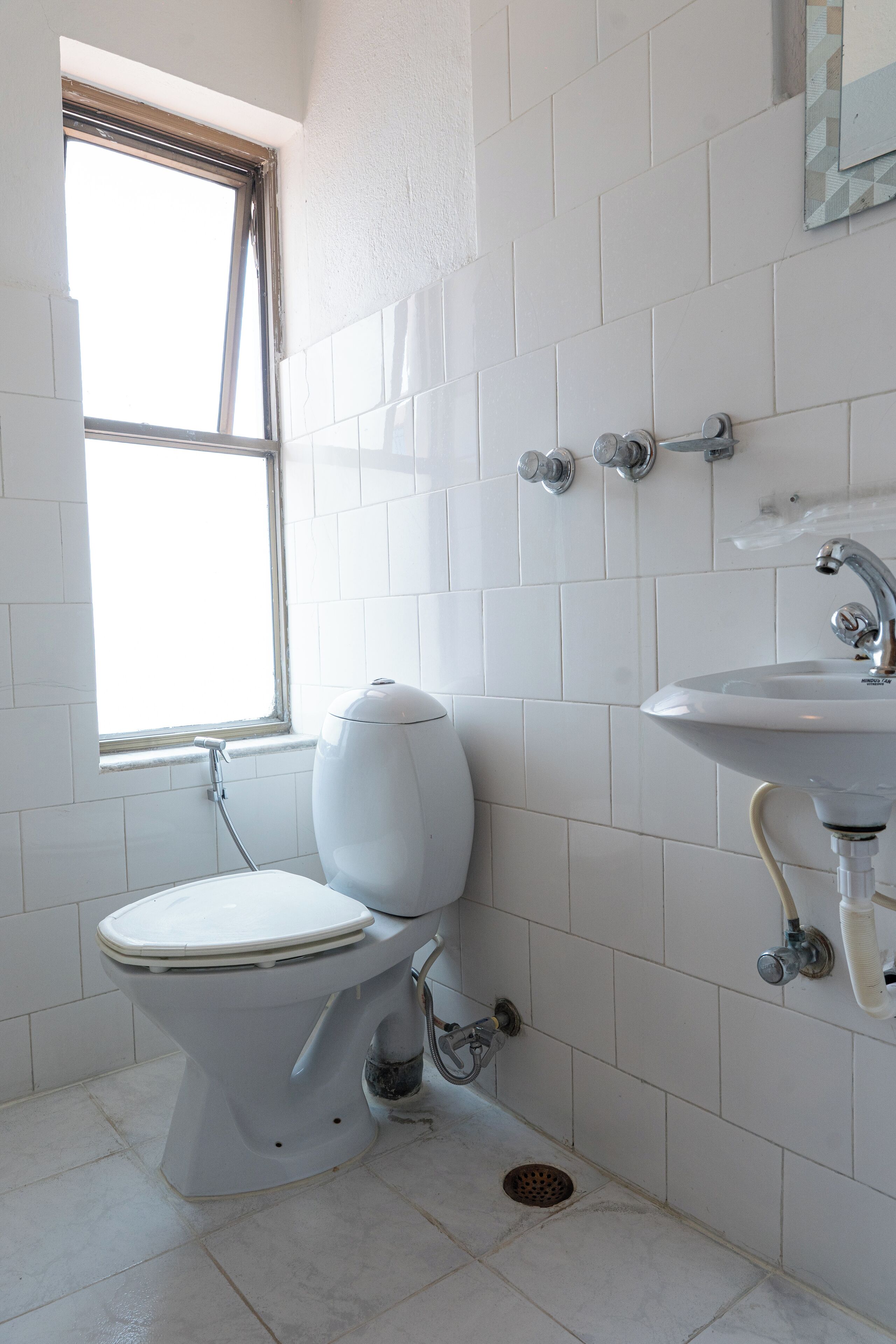 Une salle de bain avec des toilettes, un lavabo et une fenêtre.