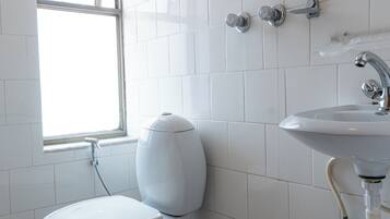 Une salle de bain avec des toilettes, un lavabo et une fenêtre.