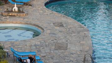 A pool area with blue lounge chairs, a stone deck, and a Club Bagel building in the background.